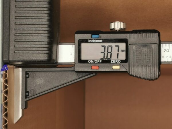 Close-up of a digital caliper reading about 7.97 mm, with the knurled thumb wheel and measurement scale visible.