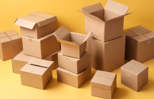 Pile of assorted cardboard boxes on a bright yellow background, with some open and others closed.