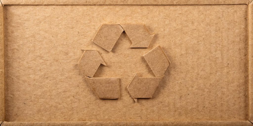 Cardboard box with a cut-out recycling symbol in the center.