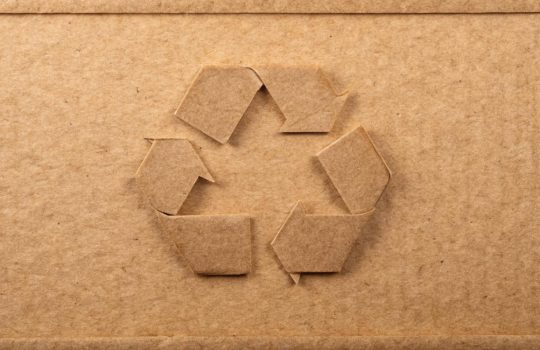 Cardboard box with a cut-out recycling symbol in the center.