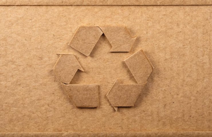 Cardboard box with a cut-out recycling symbol in the center.
